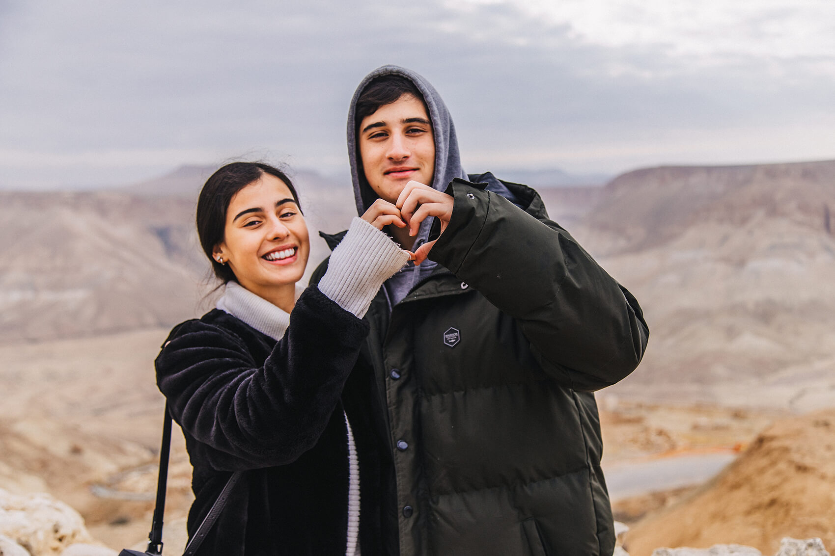 Two Birthright Israel participants forming a heart with their hands in the Negev)